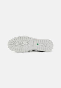 Suola di scarpa in gomma bianca con un pattern di presa testurizzato e il logo Timberland. Presenta un accento verde vicino al tallone e una superficie liscia.