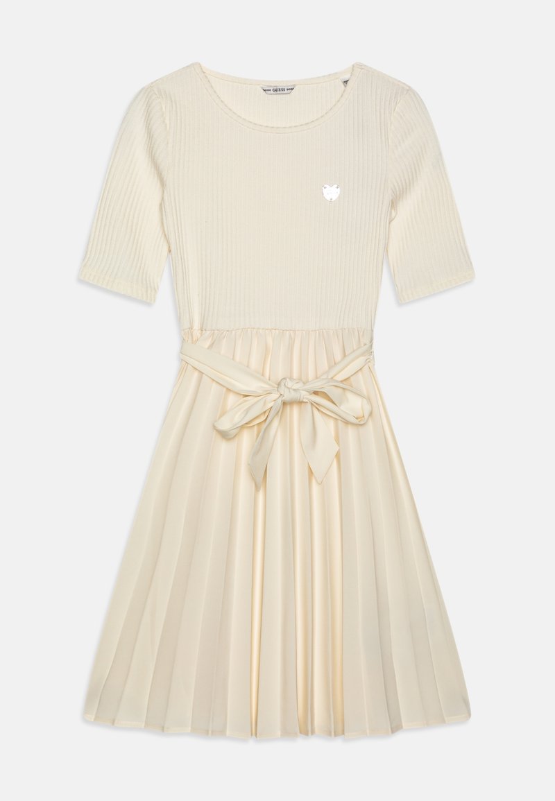 Vestido top de canalé color crema con falda plisada de tela similar a la seda, con cinturón anudado en la cintura y un pequeño emblema de logo en el pecho.