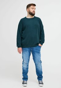 Tume rohelise tekstuuriga sviiter ümmarguse kaelusega, mille on kombineeritud helesiniste teksade ja must-valgete tossudega. Lihtne disain, mugav lõige.