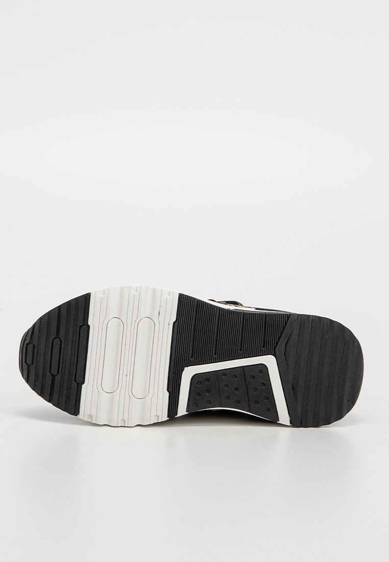 Sohle eines schwarz-weißen Sportschuhs mit strukturiertem Profil, vor einem schlichten weißen Hintergrund gezeigt.