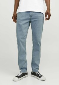 Jeans drept, de culoare albastru deschis, cu un design clasic cu cinci buzunare, fabricate din țesătură de denim. Combinate cu adidași negri cu accente albe.