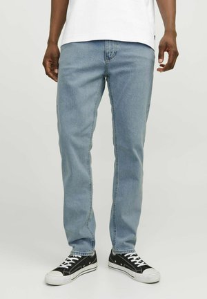 Jeans de pierna recta en azul claro con un diseño clásico de cinco bolsillos, fabricados en tela de mezclilla. Combinados con zapatillas negras con detalles en blanco.