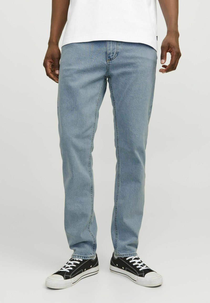 Jeans drept, de culoare albastru deschis, cu un design clasic cu cinci buzunare, fabricate din țesătură de denim. Combinate cu adidași negri cu accente albe.