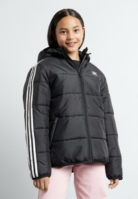Black puffy jacket with a hood, featuring white three-stripe accents on sleeves and a small logo on the chest. Zippered front, quilted texture.