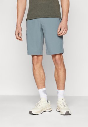 Himmelblaue Shorts mit geradem Schnitt, ausgestattet mit Seitentaschen und einer glatten Textur, kombiniert mit cremefarbenen Sneakers und weißen Socken.