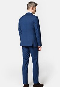 Niebieski garnitur w kratę o dopasowanym fasonie, z teksturowanej tkaniny i wąskich spodni. Zawiera klapy z wycięciem, boczne rozcięcia oraz zapinane mankiety.