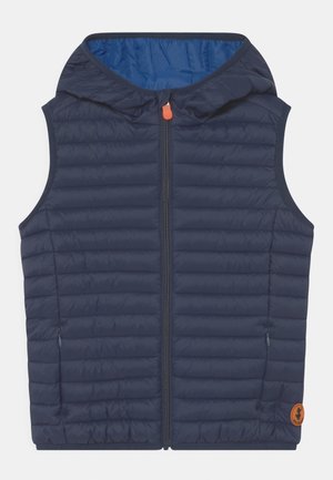 Veste sans manches matelassée bleu marine avec capuche, fermeture éclair à l'avant, poches latérales zippées et petit patch logo rond orange près de l'ourlet.