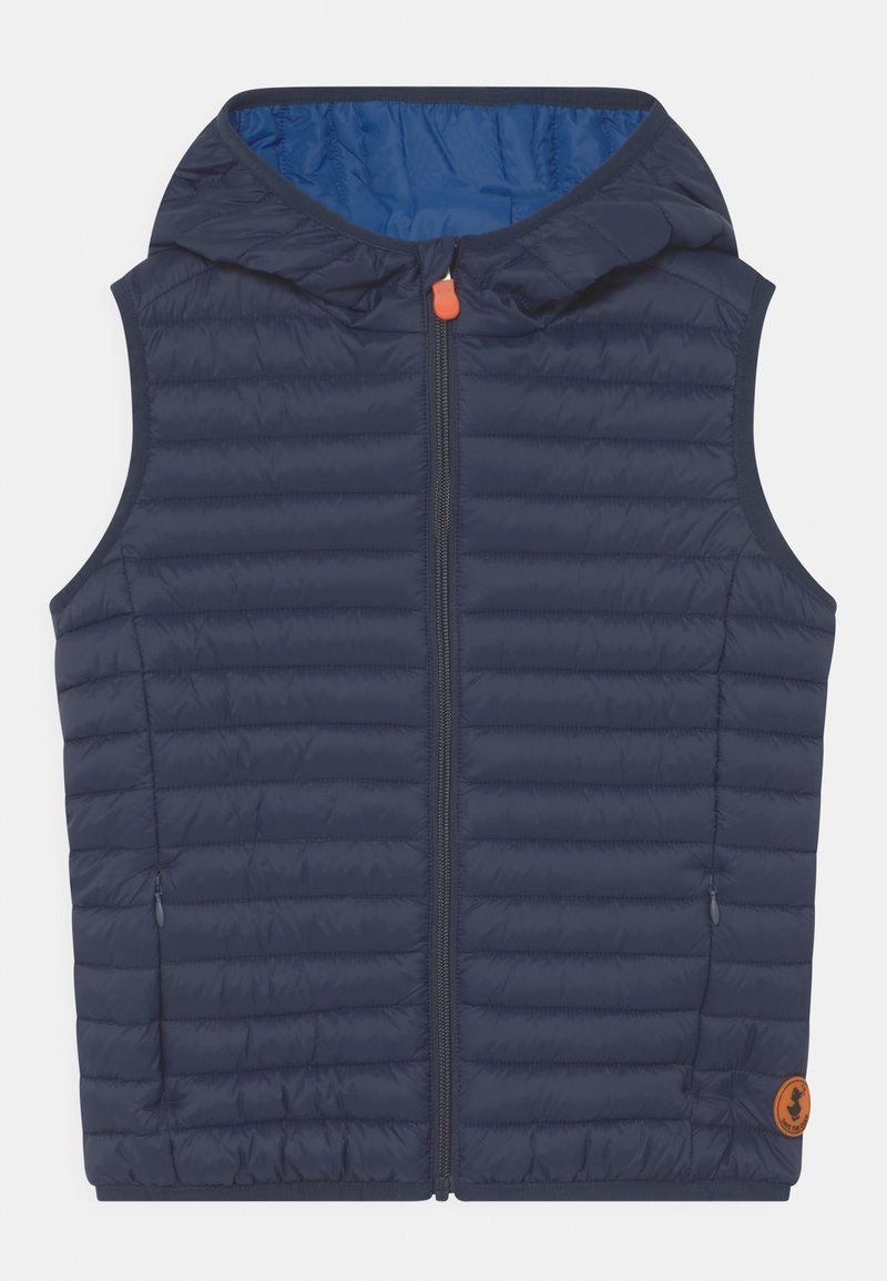 Veste sans manches matelassée bleu marine avec capuche, fermeture éclair à l'avant, poches latérales zippées et petit patch logo rond orange près de l'ourlet.