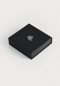Fekete téglalap alakú doboz sima felülettel, középen ezüst "RL" logóval a tetején. Minimál stílusú design.