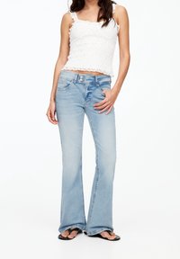 Jeans a zampa d'elefante di colore azzurro chiaro con vita a media altezza. Realizzati in tessuto denim, presentano tasche frontali e un effetto di lavaggio leggero.