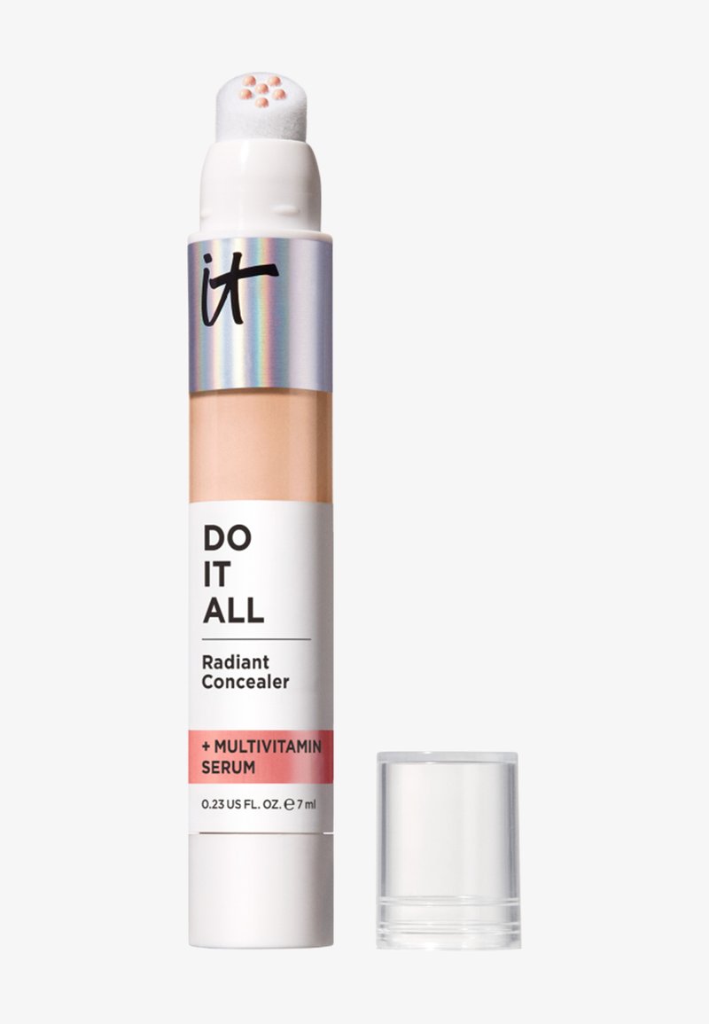 Bâton correcteur avec éponge applicatrice montrant une crème beige et un capuchon en plastique transparent à côté, sur fond blanc.