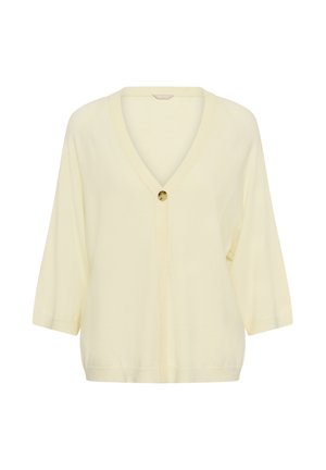 Kreminės spalvos megztinis su trijų ketvirčių rankovėmis ir viena didelė ruda saga per vidurį priekyje, žemiau V formos iškirptės.