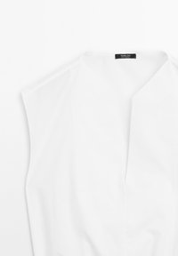 White sleeveless blouse with a V-neck design, featuring minimal seams and a smooth texture. Label reads "Massimo Dutti."