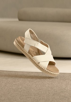 Άσπρο δερμάτινο σανδάλι με λουράκια που διασταυρώνονται στην πλάτη και κεντημένη περίμετρο σε στιλ εσπαντρίγιας. Λείο επάνω μέρος και αναπαυτική εσωτερική σόλα.