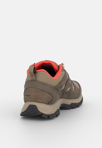 Wodoodporny but do wędrówek w kolorach brązowym i beżowym, z teksturowaną cholewką z zamszu, siateczkowymi akcentami oraz jaskrawoczerwonym wnętrzem i amortyzowaną podeszwą.