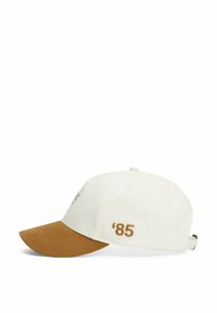 Gorra de béisbol blanca con visera marrón, presenta texto bordado en la parte delantera y lateral, y una correa ajustable en la parte posterior.