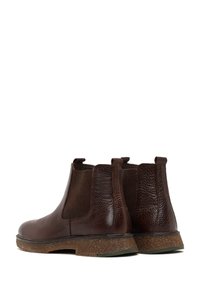 Botas Chelsea de cuero marrón con un acabado texturizado, paneles laterales elásticos y suela de tipo corcho. Cuenta con tiradores para ponérselas fácilmente.