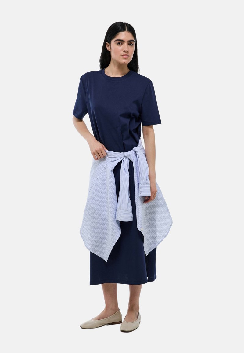 Robe en coton bleu marine à manches courtes, associée à une chemise rayée bleu clair nouée à la taille. Tissu doux et lisse avec un design simple.