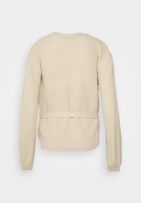 Maglione beige a maglia con maniche lunghe, polsi a coste e vita con cintura. Il tessuto testurizzato aggiunge profondità al design.