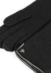Schwarze Wollhandschuhe mit einem glatten Lederbesatz am Bund und einem metallischen Logo-Detail, die über eine strukturierte, warme Oberfläche verfügen.