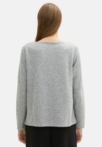Šedý pletený svetr s kulatým výstřihem, dlouhými rukávy a mírně volným střihem, s jemnou texturou a minimalistickým designem.