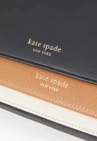Leather wallet featuring black, tan, and white sections with a textured surface. Gold "kate spade NEW YORK" logo displayed prominently.