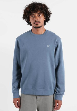 Sweat-shirt en coton bleu à manches longues, col rond, avec un logo blanc sur la poitrine. Texture lisse, coupe décontractée, poignets et ourlet côtelés.