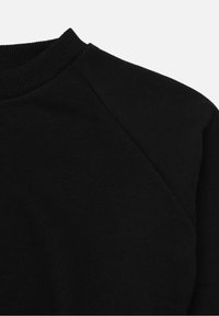 Felpa nera con collo a girocollo e dettagli in cucitura diagonale sulla spalla, presentata su uno sfondo bianco semplice.