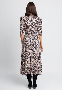 Sukienka midi w odcieniu beżowym z ciemnymi paskami zebry, z bufkami na rękawach, paskiem w talii i zwiewną spódnicą. Wykonana z miękkiego, teksturowanego materiału.
