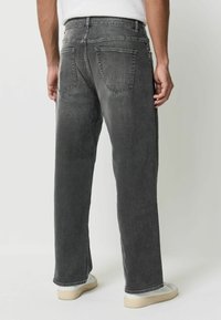 Szare dżinsy z prostymi nogawkami, z dwoma tylnymi kieszeniami i delikatnymi przetarciami. Noszone z jasnym obuwiem.