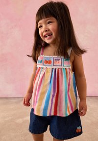 Striped, sleeveless top with multicolored horizontal stripes and fruit embroidery. Paired with denim shorts featuring a cherry design.