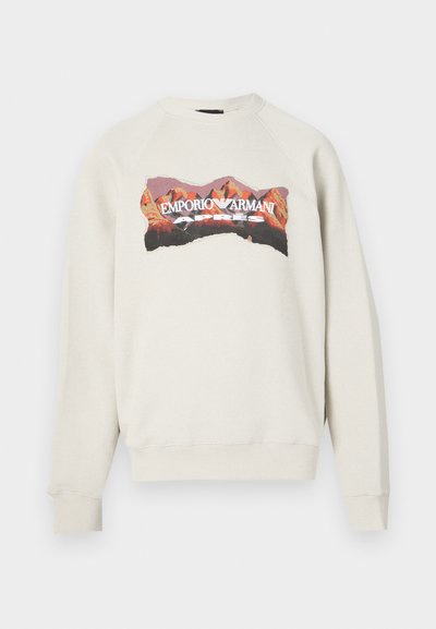 Jasnoszara bluza z okrągłym dekoltem i rękawami raglanowymi. Z kolorową grafiką przedstawiającą góry oraz napisem "EMPORIO ARMANI APRES".