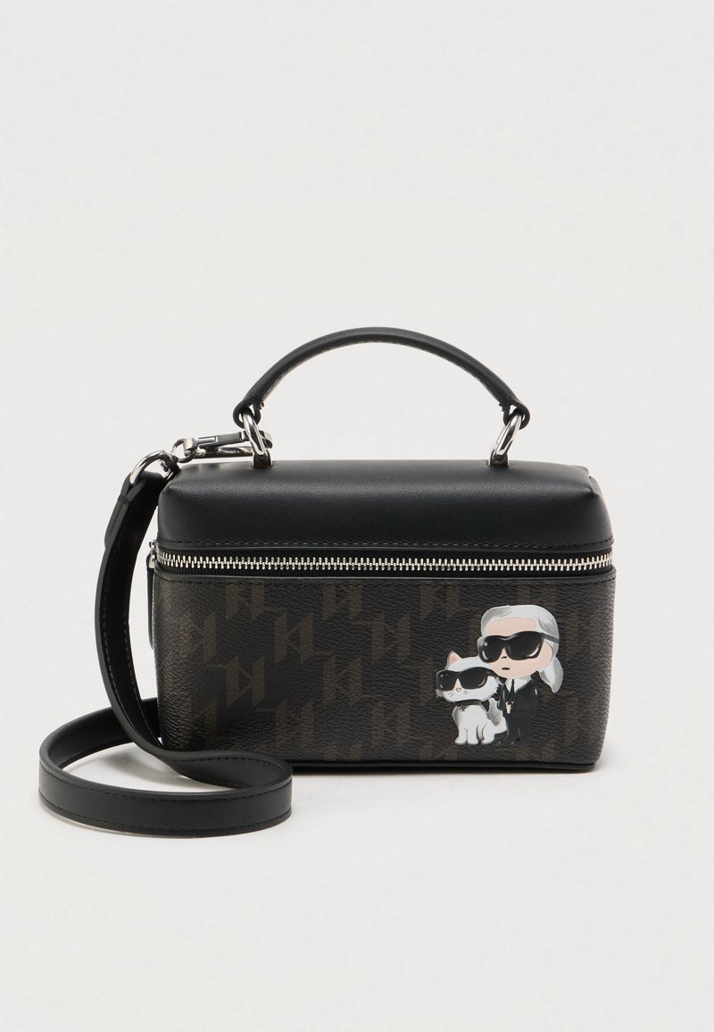 Melna ādas soma ar rāvējslēdzēja aizdari, uz kuras ir zīmēta karikatūras grafika ar cilvēku un kaķi. Komplektā ir noņemams plecu siksniņa.