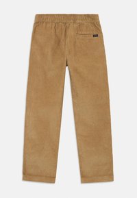 Corduroy pants in light brown, featuring an elastic waistband, straight cut, and back pocket with a small label. Texture is ribbed.