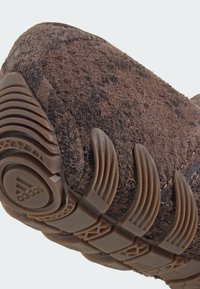 Close-up of brown Adidas shoe sole with textured rubber grip and suede upper material.