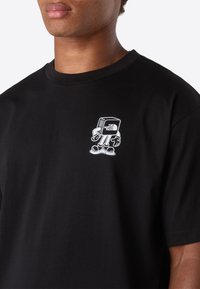 Černé tričko s malou bílou kreslenou grafikou chodícího kvádru, na prsou s logem "The North Face".