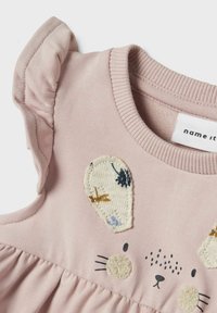 Różowa bawełniana sukienka z krótkimi falbaniastymi rękawami, teksturowanymi uszami królika, haftowanymi szczegółami na twarzy oraz marszczonym stanem.