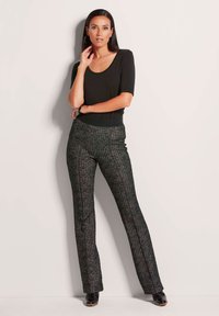 Zwart kortemouwen top en gestreepte zwarte broek met multicolore accenten; gladde textuur en getailleerde snit, gecombineerd met zwarte schoenen.