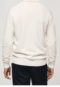 White knitted sweater with a round neckline and ribbed cuffs and hem. Fabric appears soft with a smooth texture. Back view shown.