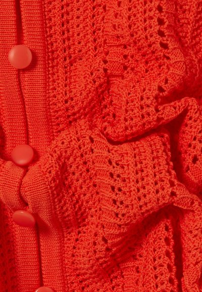 Tela de punto roja brillante con un intrincado patrón calado y botones rojos a juego a lo largo de un borde acanalado.