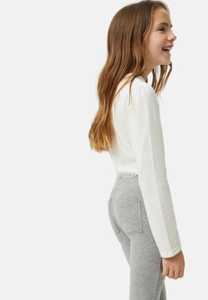 Top blanco de manga larga combinado con pantalones ajustados grises. El top tiene un diseño sencillo, mientras que los pantalones presentan una tela texturizada y elástica.