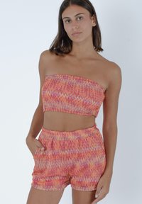 Set di top corto senza spalline e pantaloni corti con motivo zigzag multicolore. Realizzato in tessuto leggero con vita elastica e tasche.