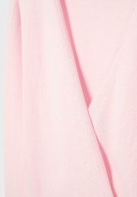 Meka ružičasta tkanina s detaljem preklapanja u obliku slova V, koja prikazuje teksturu i fine šavove na odjevnom predmetu.