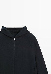 Zwarte zip-up hoodie met aangehechte capuchon en zilveren ritssluiting, van voren weergegeven op een witte achtergrond.