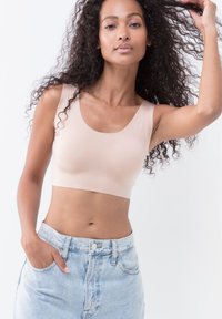 Beige crop top med brede stropper, glat tekstur og tætsiddende design. Båret med højtaljede lyseblå denim shorts.