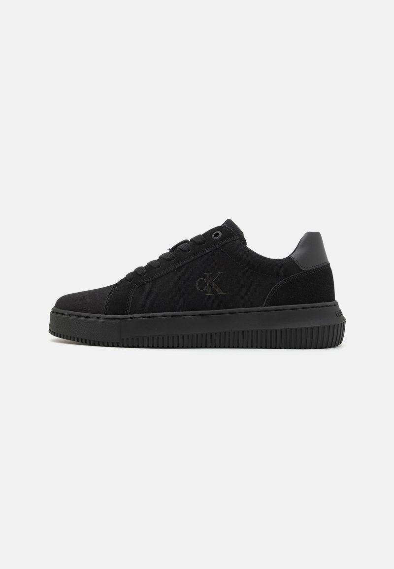 Fekete vászon sneaker, szarvasbőr részletekkel, lapos gumitalppal, kerek orral és logóval az oldalon. Minimalista dizájn.