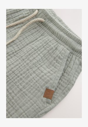 Svetlozelené bavlnené šortky s textúrou a elastickým pásom. Detailom je svetločokoládový kožený štítok s logom a kontrastný šnúrka na sťahovanie.