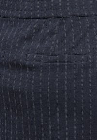 Marineblauer Stoff mit dünnen vertikalen Streifen; verfügt über eine Gesäßtasche mit einer geraden Naht. Das Material hat eine strukturierte Oberfläche mit leichtem Glanz.
