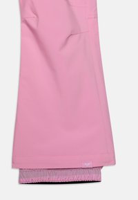 Helle rosa wasserdichte Hose mit elastischen Bündchen, abgesteppten Nähten und einem kleinen Logoetikett am Saum. Glatte Materialstruktur.