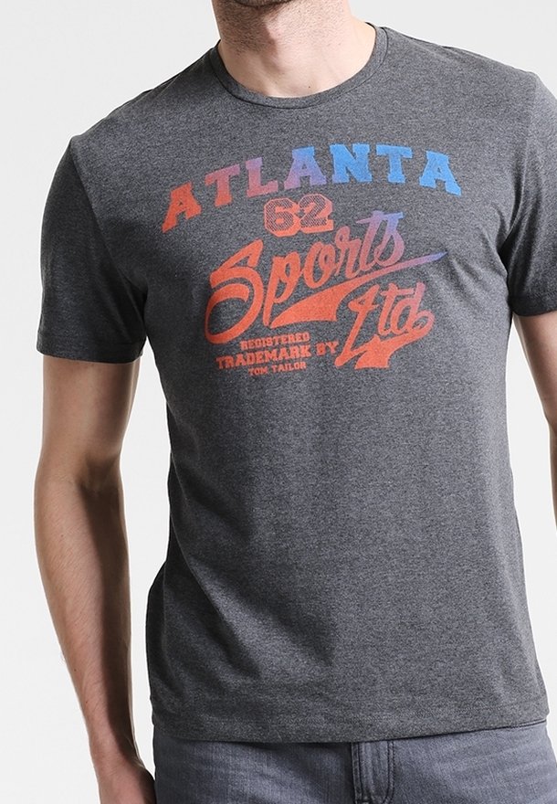 Homme portant un t-shirt gris foncé avec un texte multicolore indiquant « Atlanta 62 Sports Ltd Registered Trademark by Tom Tailor. »